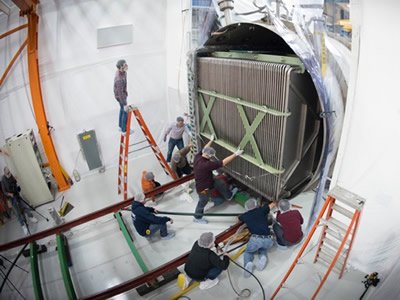 Scientists work on the MicroBooNE detector, which is approximately the size of a school bus (Courtesy of Fermilab)
