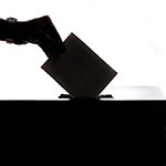 Silhouette of person inserting a ballot into a box
