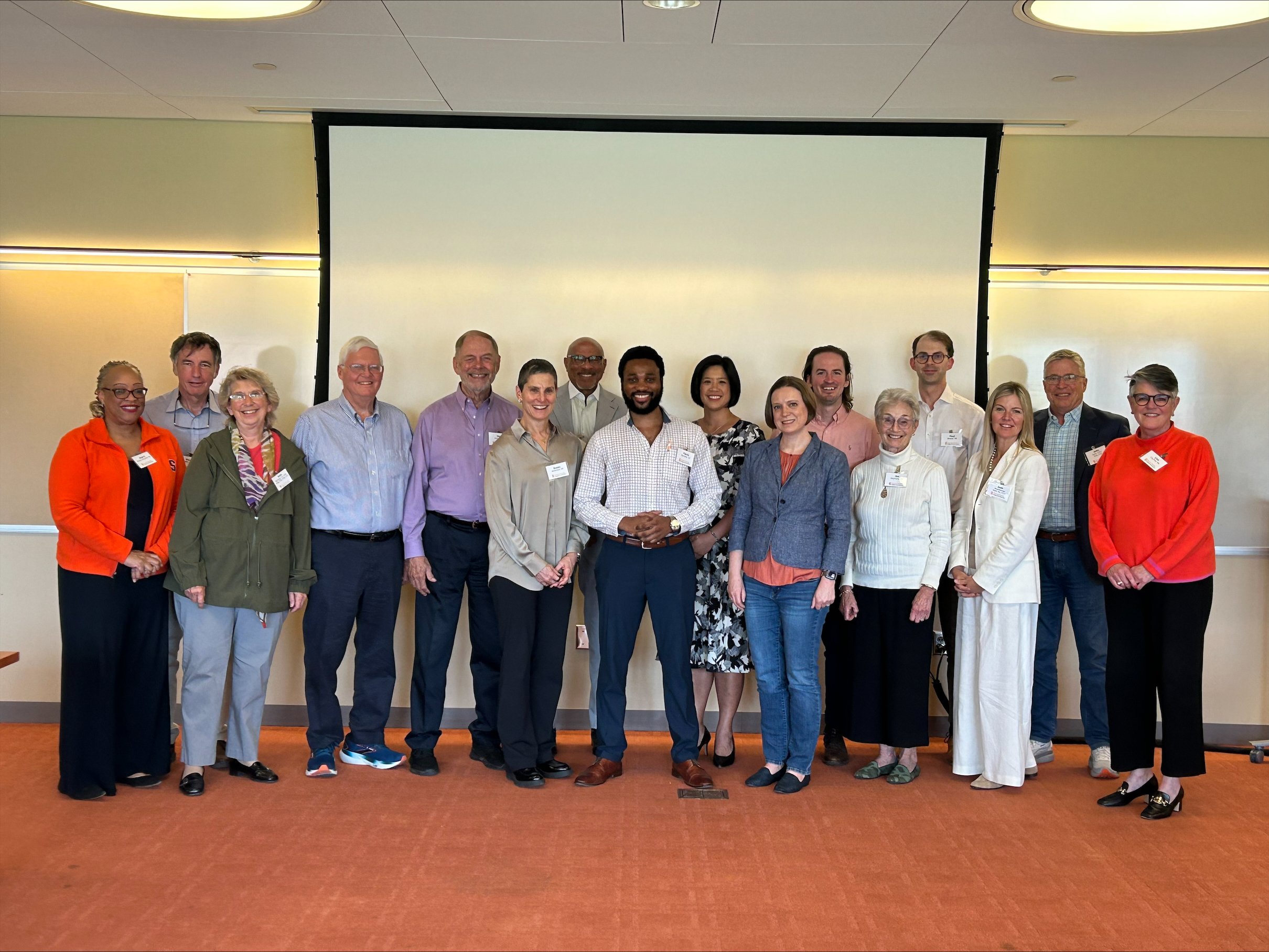 Group of people standing in front of a projection screen.