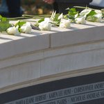 Students in front of Wall of Remembrance memorial with white roses