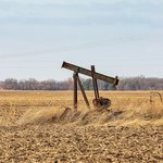 Orphaned oil well pump in farm field
