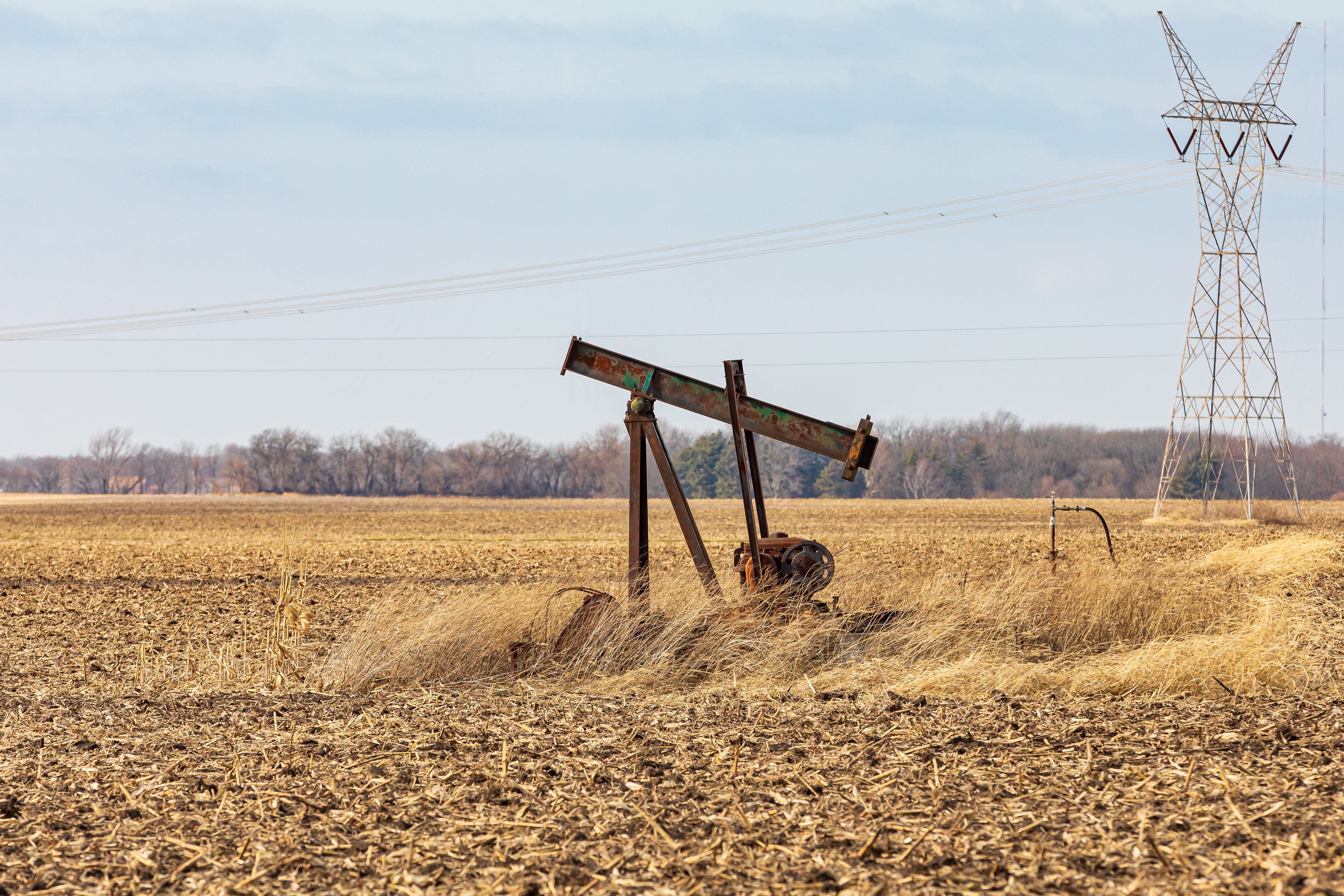 Orphaned oil well pump in farm field