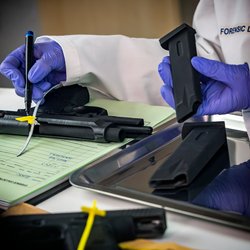 Police scientist notes serial number on sealed firearm in crime lab, conceptual image