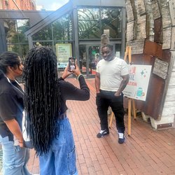 Person being interviewed on a sidewalk.